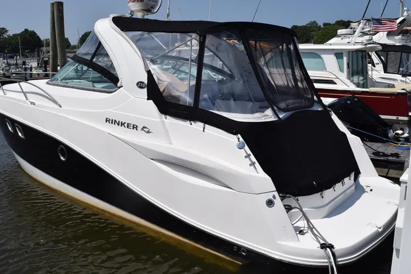 Slide: The Image of 2010 Rinker 310 Express Cruiser docked at marina, featuring sleek design and black canopy. - 1