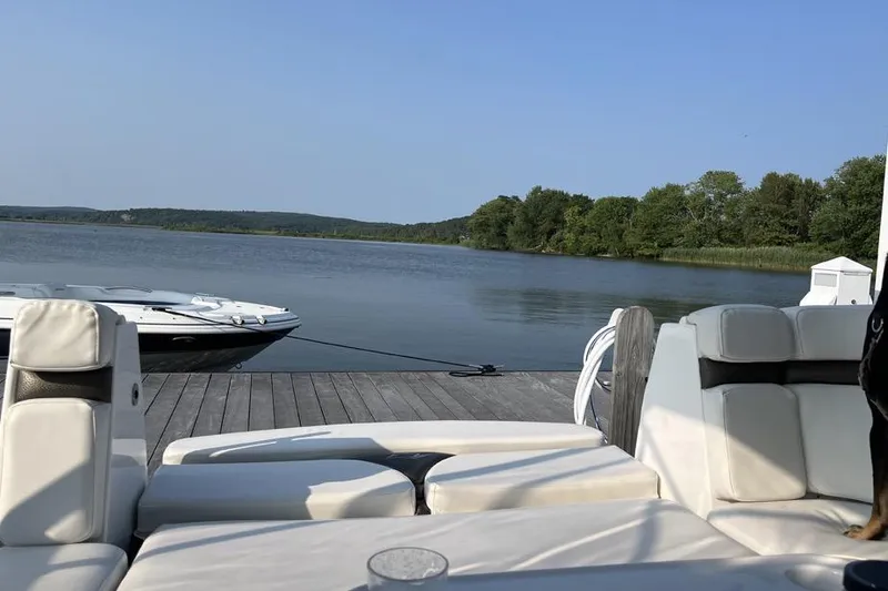 Slide: The Image of 2010 Rinker 310 Express Cruiser docked on a serene lake with lush green surroundings. - 12