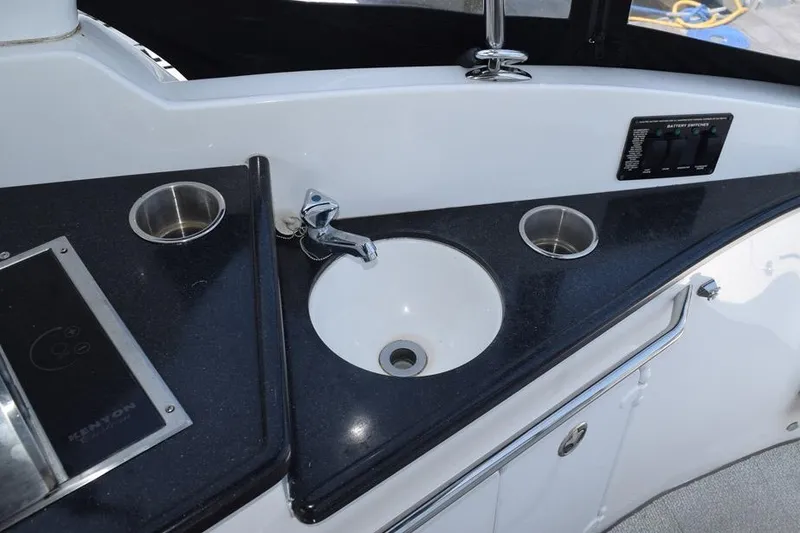 Slide: The Image of 2010 Rinker 310 Express Cruiser kitchenette with sink and cup holders. - 13