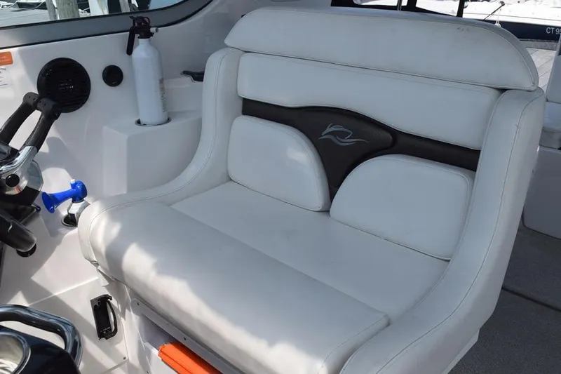 Slide: The Image of 2010 Rinker 310 Express Cruiser helm seat with white upholstery and control panel. - 17