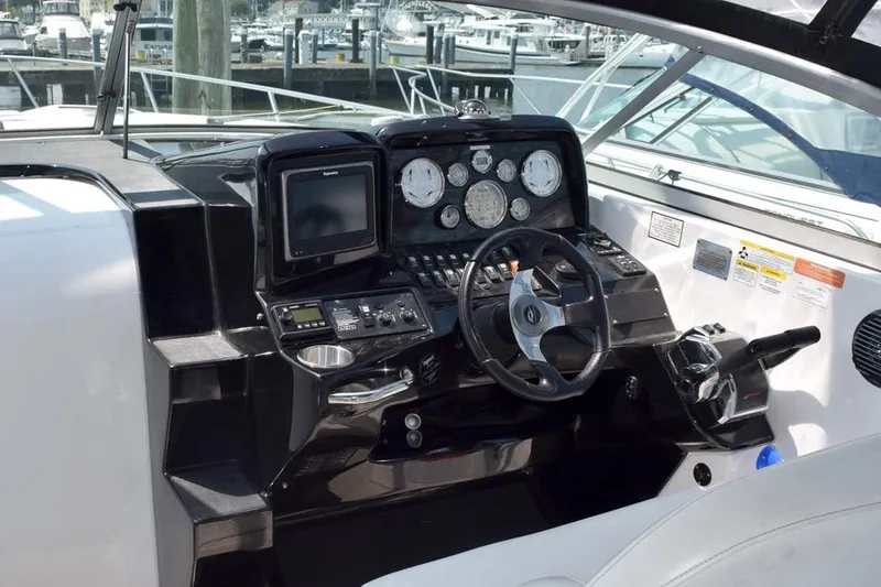 Slide: The Image of 2010 Rinker 310 Express Cruiser helm with gauges, steering wheel, and navigation controls. - 18
