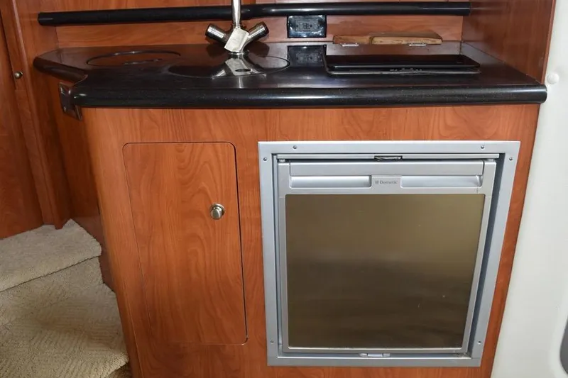 Slide: The Image of 2010 Rinker 310 Express Cruiser kitchenette with sink, stove, and compact refrigerator. - 30