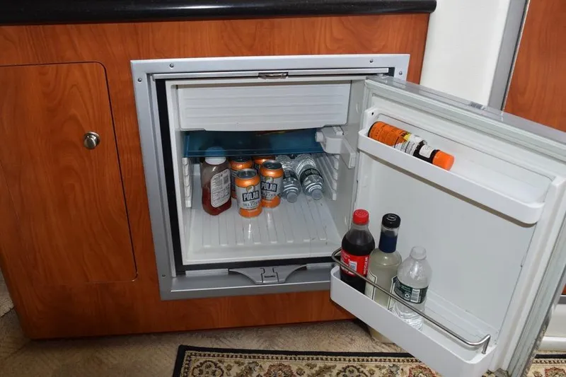 Slide: The Image of Mini fridge stocked with beverages inside a 2010 Rinker 310 Express Cruiser. - 31