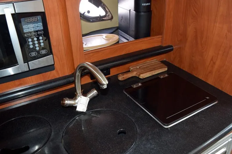 Slide: The Image of 2010 Rinker 310 Express Cruiser kitchen with microwave, sink, and cutting board. - 35