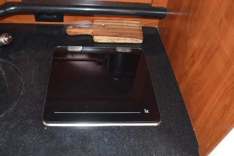 Slide: The Image of 2010 Rinker 310 Express Cruiser kitchen with black countertop and cutting board. - 36