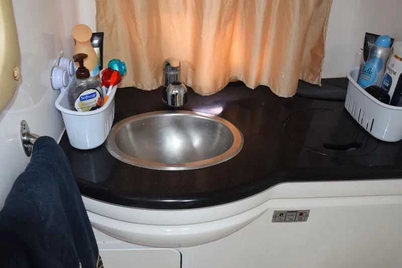 Slide: The Image of 2010 Rinker 310 Express Cruiser bathroom sink with toiletries and towel. - 43