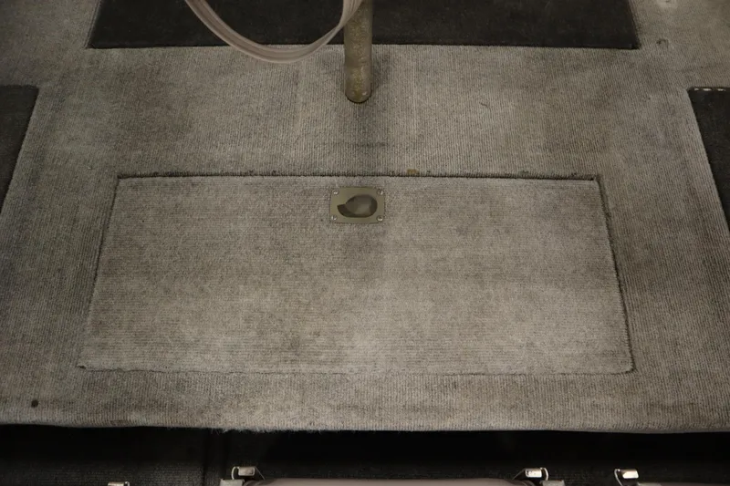 Slide: The Image of Carpeted floor of a 1997 Tracker 18 Pro Team SC boat, featuring a hatch cover. - 36