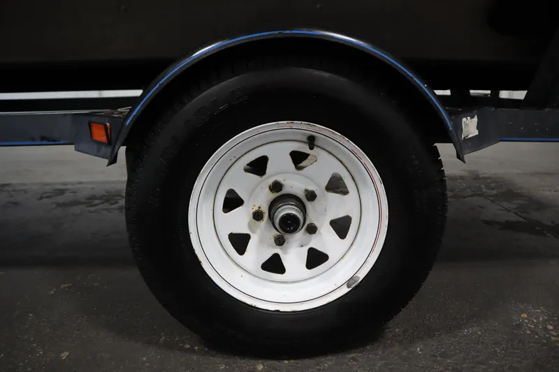 Slide: The Image of Trailer wheel of a 1997 Tracker 18 Pro Team SC boat, featuring white rim and black tire. - 48
