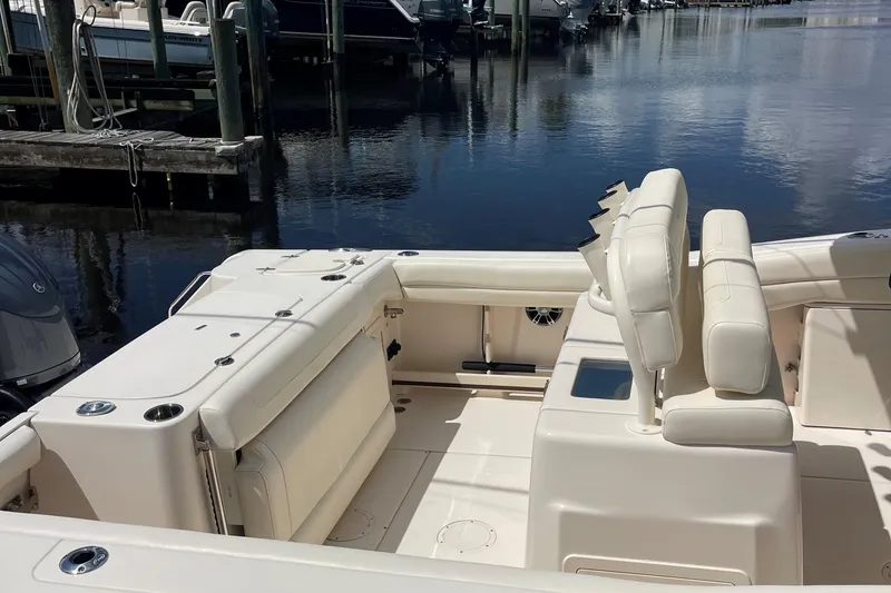 Slide: The Image of 2022 Grady-White Canyon 271 boat interior with seating, docked by calm water. - 11