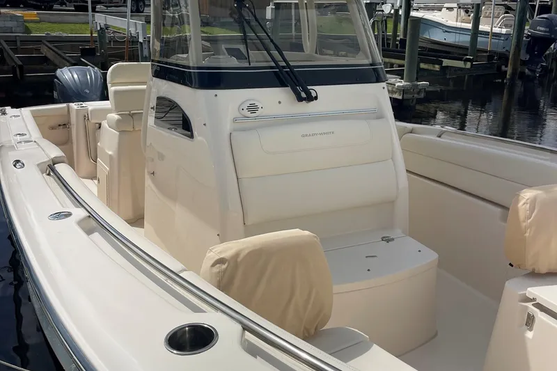 Slide: The Image of 2022 Grady-White Canyon 271 boat interior with seating and console, docked at marina. - 12