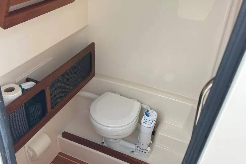 Slide: The Image of 2022 Grady-White Canyon 271 boat bathroom with toilet and storage shelves. - 20