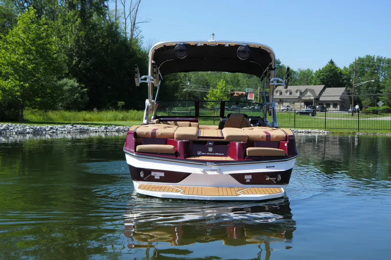 Slide: The Image of 2023 MasterCraft XT20 boat on calm water, surrounded by lush greenery. - 2