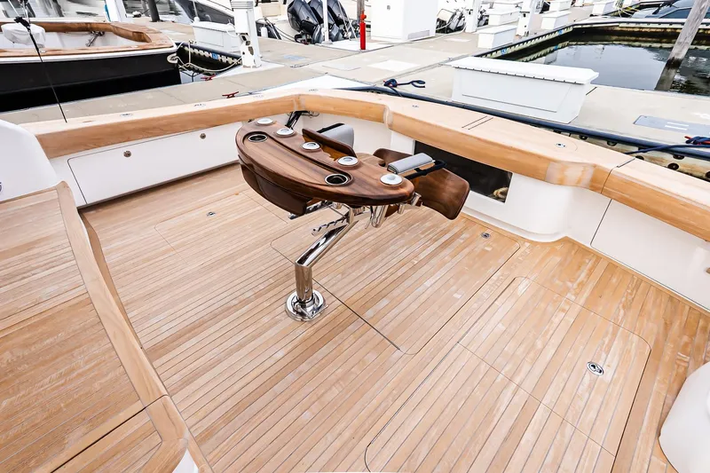 Slide: The Image of 2026 Viking 64 Convertible yacht deck with polished wood finish and fishing chair. - 11