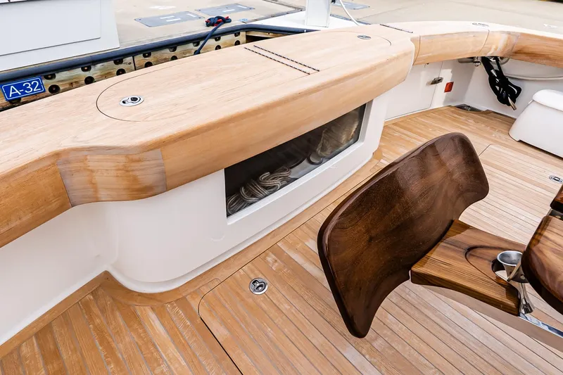 Slide: The Image of 2026 Viking 64 Convertible yacht deck with wooden seating and storage. - 21