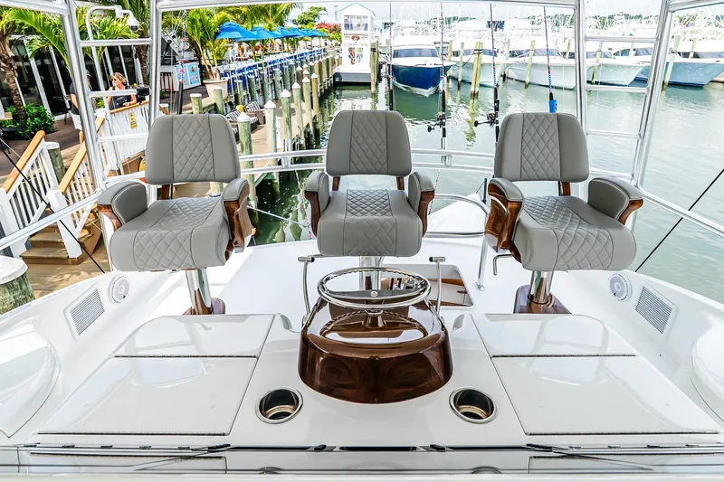 Slide: The Image of Luxury seating on 2025 Viking 64 Convertible yacht, docked at marina with boats in background. - 45