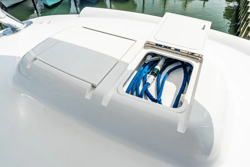 Slide: The Image of 2025 Viking 64 Convertible yacht deck with storage compartment and blue hoses. - 61