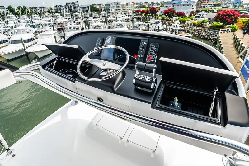 Slide: The Image of Helm of 2025 Viking 64 Convertible yacht at marina, featuring modern controls and steering. - 63
