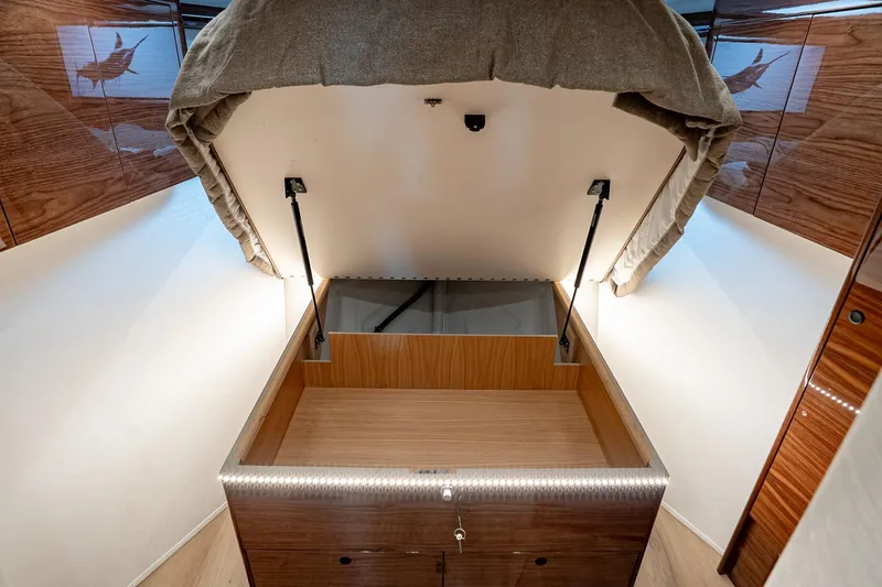 Slide: The Image of 2026 Viking 64 Convertible yacht interior with open storage compartment and wood paneling. - 70