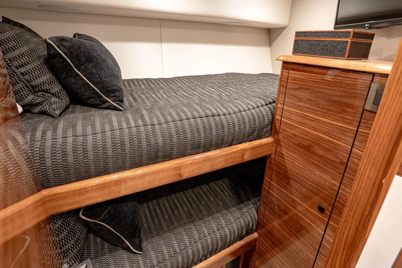 Slide: The Image of 2026 Viking 64 Convertible yacht interior with cozy bunk beds and elegant wood finish. - 76