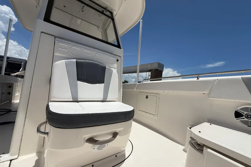 Slide: The Image of 2020 Robalo R272 Center Console boat interior with cushioned seating under clear blue sky. - 16