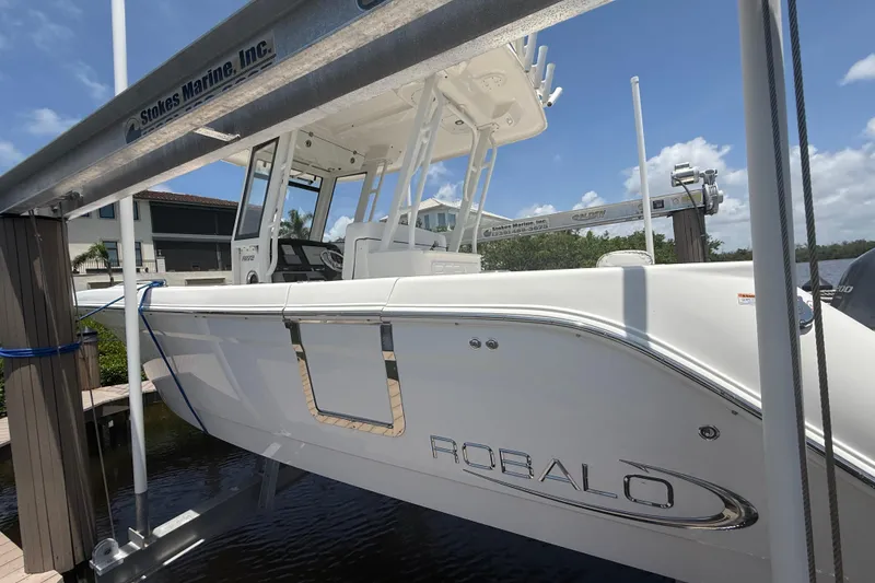 Slide: The Image of 2020 Robalo R272 Center Console boat on lift, sunny day, marina background. - 36