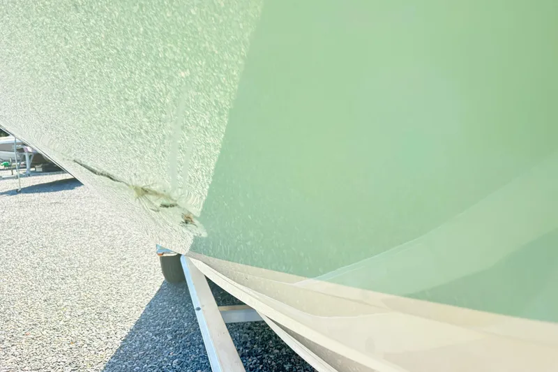 Slide: The Image of 2022 Grady-White 251 Coastal Explorer boat hull with visible damage on trailer. - 8