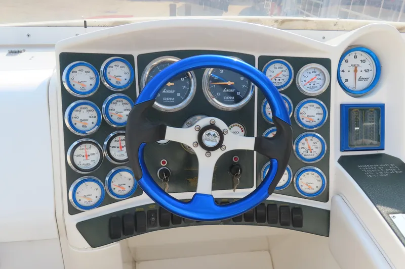 Slide: The Image of Steering wheel and dashboard of a 2003 MTI 42 boat with multiple gauges. - 24