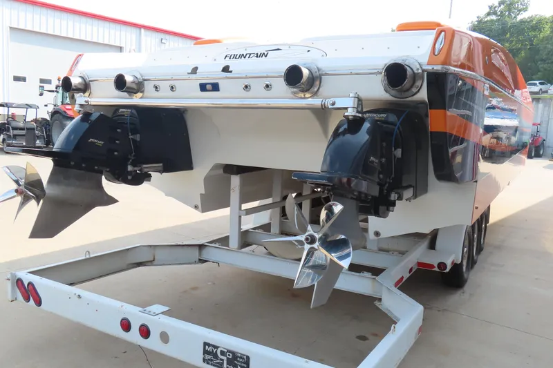 Slide: The Image of 2003 MTI 42 boat on trailer, dual propellers, orange and white design, parked outdoors. - 4
