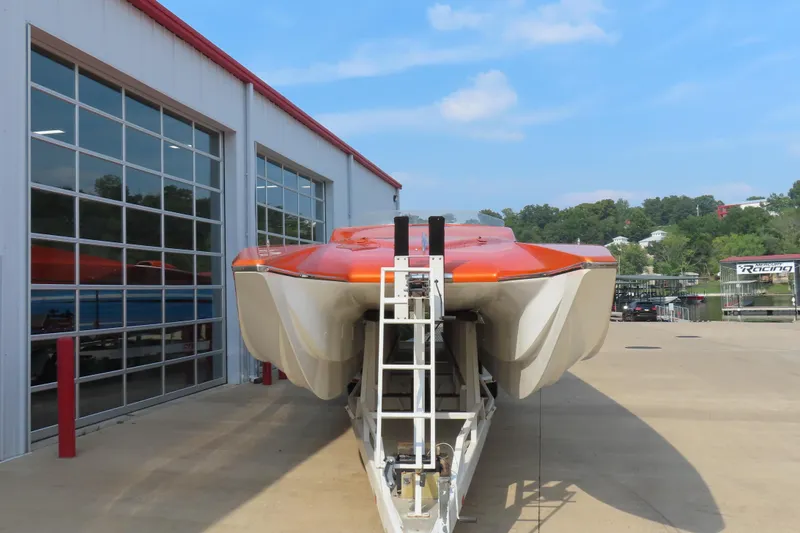 Slide: The Image of Orange MTI 42 boat on trailer outside a garage, clear sky background. - 6
