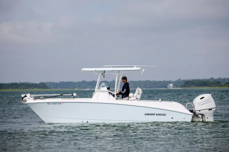 Slide: The Image of 2023 Twin Vee 240 GFX CC boat on calm water with a person at the helm. - 5