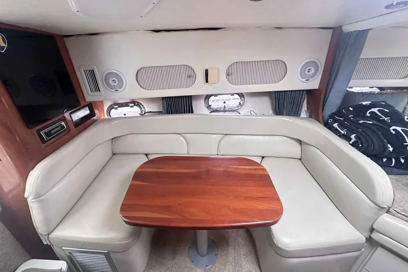 Slide: The Image of 2004 Four Winns 298 Vista cabin interior with beige seating and wooden table. - 21