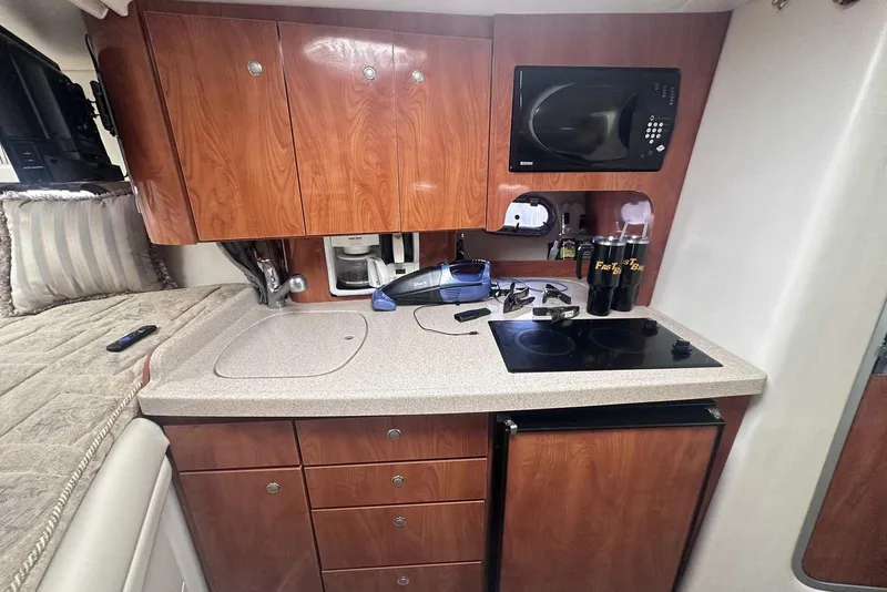 Slide: The Image of 2004 Four Winns 298 Vista boat kitchen with wooden cabinets, microwave, and stove. - 22