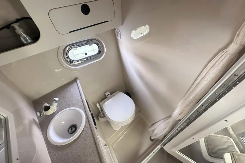 Slide: The Image of 2004 Four Winns 298 Vista boat bathroom with sink, toilet, and porthole window. - 35