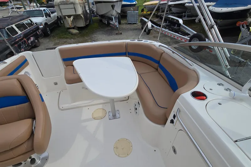 Slide: The Image of 2001 Chaparral Sunesta 233 boat interior with tan and blue seating, white table, and control panel. - 20