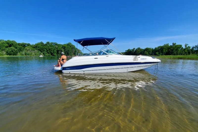 Slide: The Image of 2001 Chaparral Sunesta 233 boat on calm water with blue canopy and clear sky. - 6