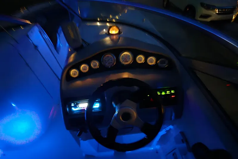 Slide: The Image of 2001 Chaparral Sunesta 233 boat dashboard illuminated with blue lights at night. - 60