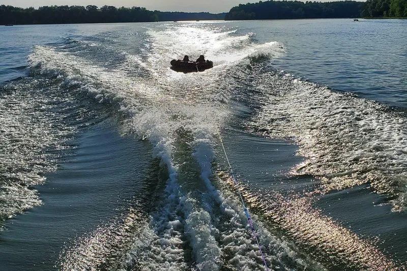 Slide: The Image of Chaparral Sunesta 233 (2001) creating waves while towing a tube on a sunny lake. - 7