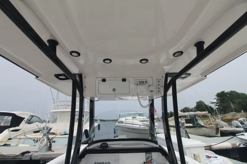 Slide: The Image of 2020 Sea Pro 259 Center Console boat interior at marina, featuring control panel and canopy. - 20