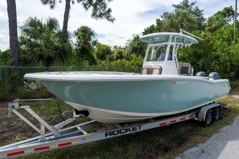 Slide: The Image of 2020 Tidewater 272 CC Adventure boat on trailer, surrounded by lush greenery. - 3