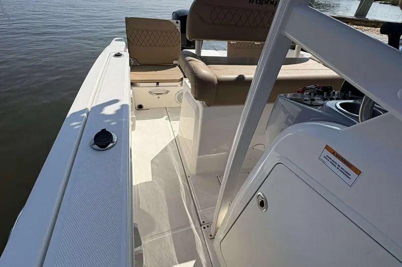 Slide: The Image of 2022 Bayliner Trophy T20CC boat interior with seating and control panel, docked by the water. - 15