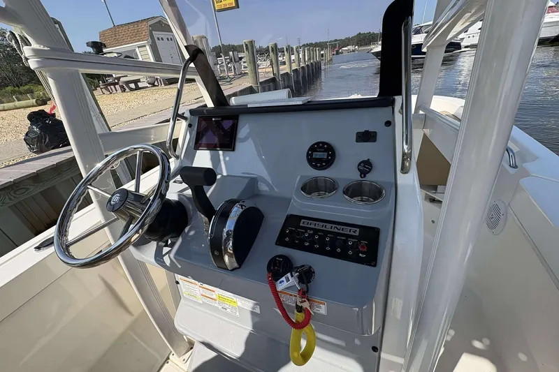 Slide: The Image of 2022 Bayliner Trophy T20CC boat console with steering wheel and controls at a marina. - 22