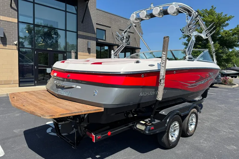 Slide: The Image of 2007 MasterCraft X15 boat with red and gray design on a trailer, parked outside a building. - 3