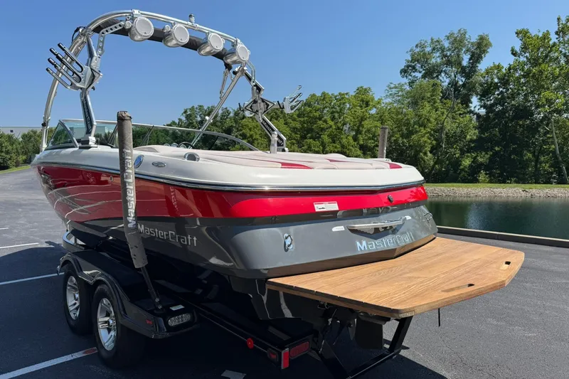 Slide: The Image of 2007 MasterCraft X15 boat on trailer, red and gray, near a lake. - 5