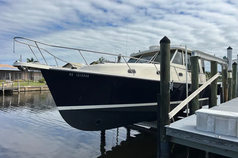 The Image of 2008 Mainship Pilot 34 boat docked at marina under cloudy sky. - 0