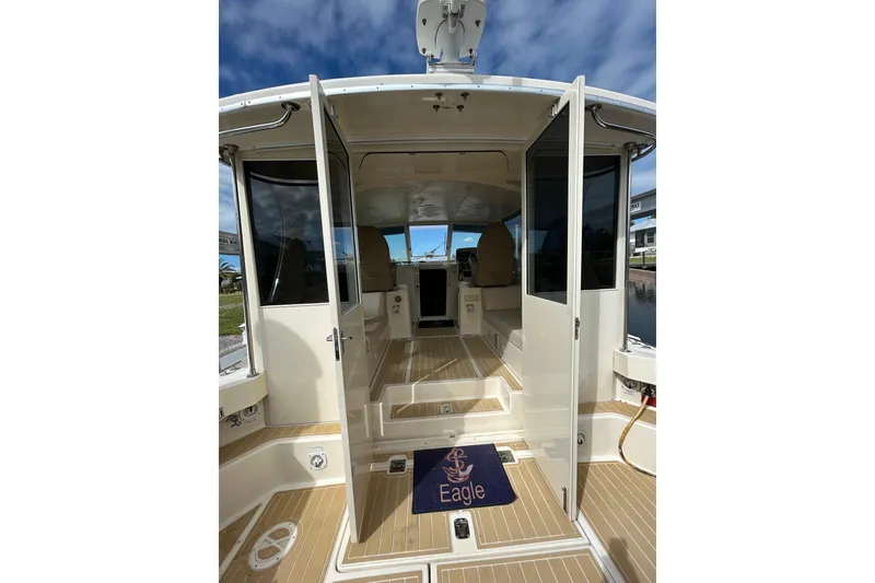 Slide: The Image of 2008 Mainship Pilot 34 boat deck with teak flooring, docked by a waterfront. - 13