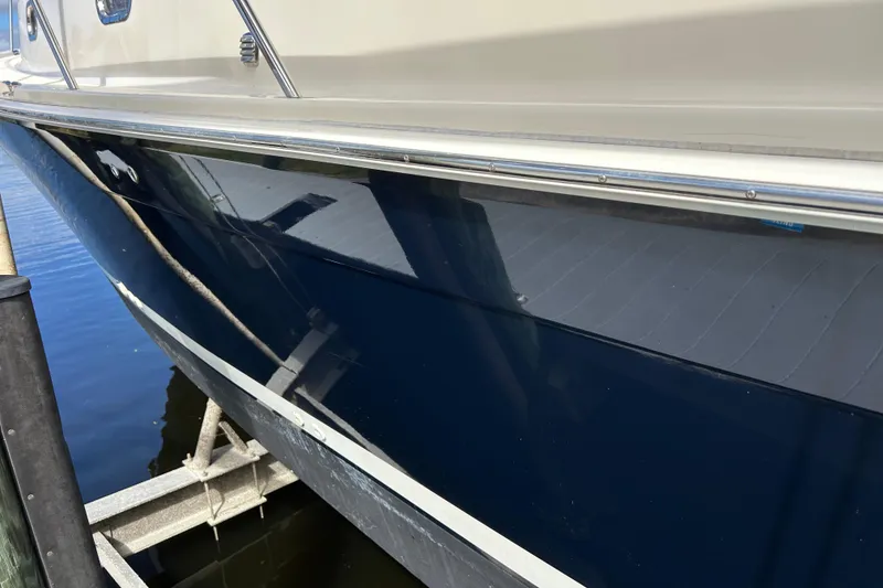 Slide: The Image of 2008 Mainship Pilot 34 boat with large windows under a clear blue sky. - 24