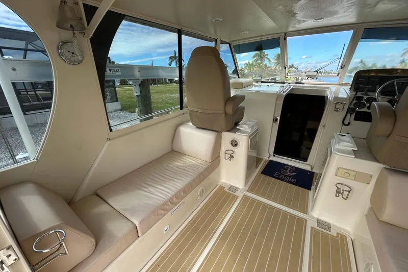 Slide: The Image of 2008 Mainship Pilot 34 interior with beige seating, helm, and dockside view. - 3