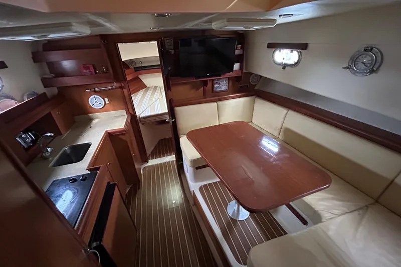 Slide: The Image of 2008 Mainship Pilot 34 interior with cozy seating, wooden table, and nautical decor. - 36