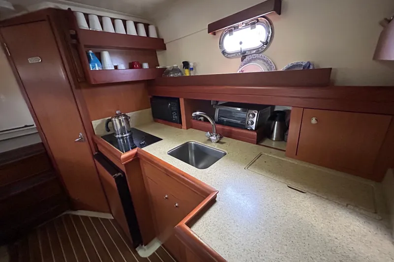 Slide: The Image of 2008 Mainship Pilot 34 galley with wooden cabinetry, sink, and appliances. - 43