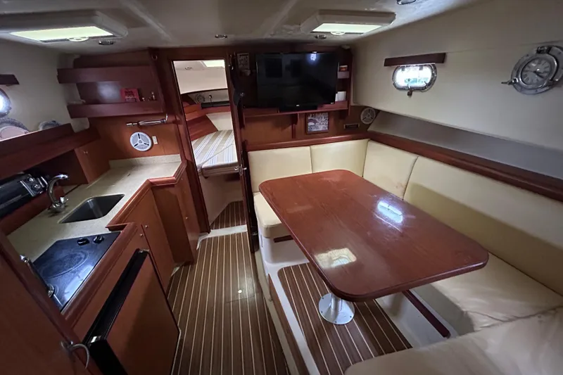 Slide: The Image of 2008 Mainship Pilot 34 interior with kitchenette, dining area, and cozy seating. - 5